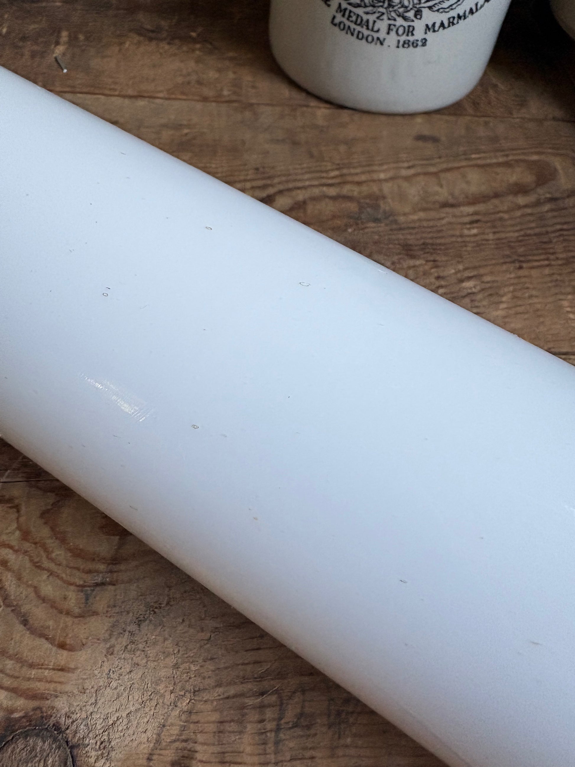 A close up picture of the white vintage roller of rolling pin on plain background