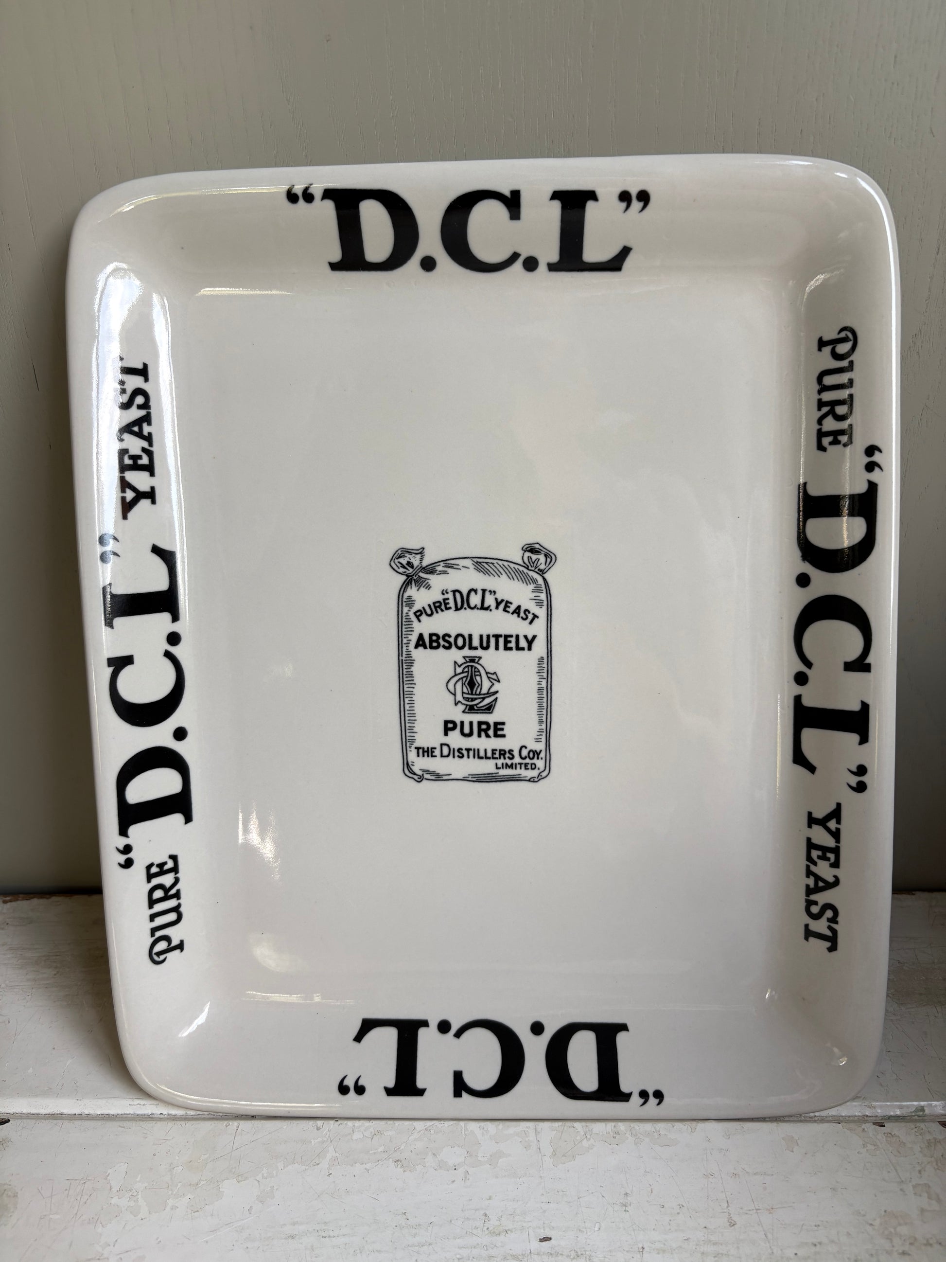 Clear front image of antique English ironstone DCL Yeast advertising shop counter display plate with black typography graphics.