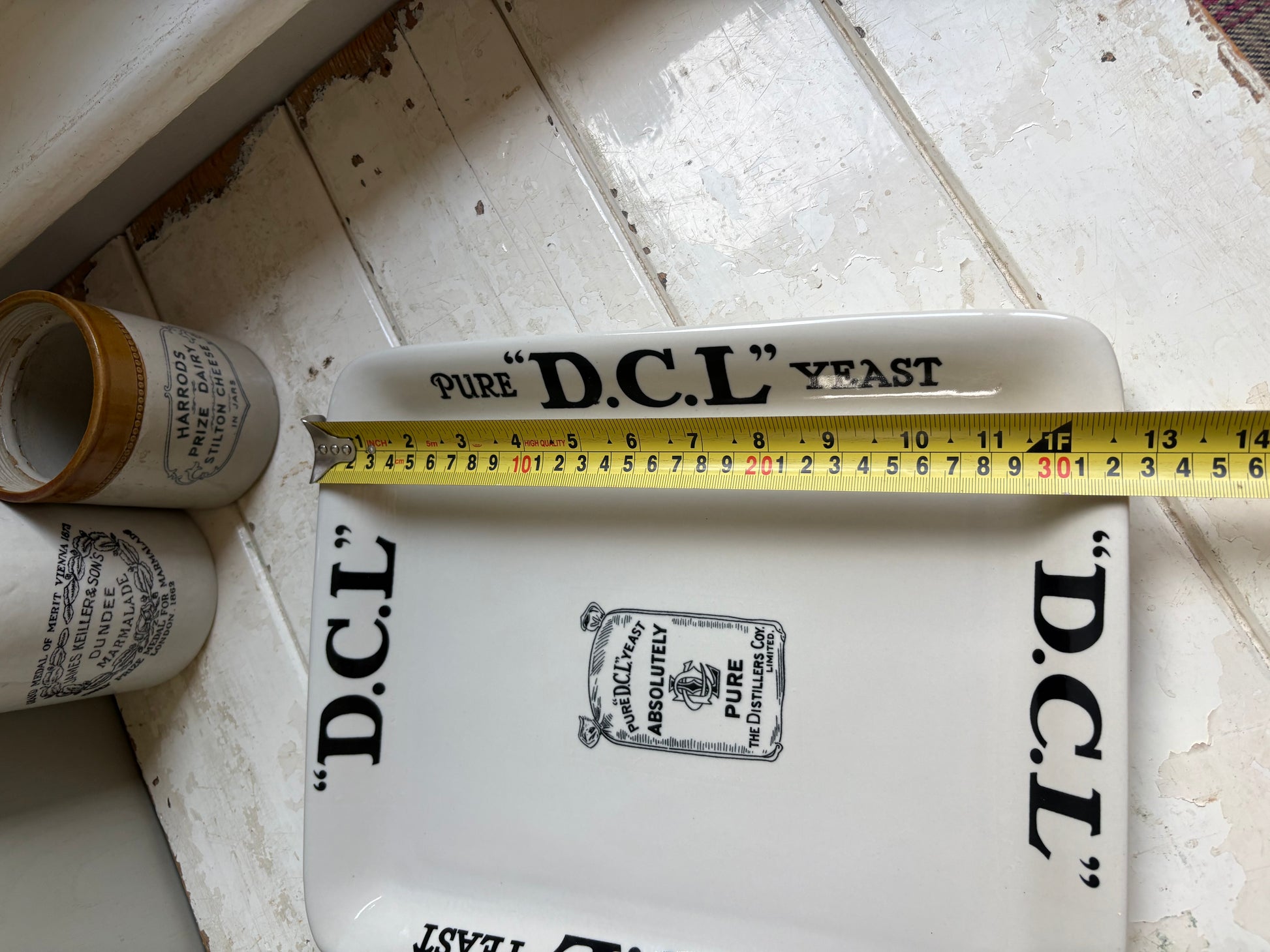 Close up image of vintage English ironstone DCL Yeast advertising display plate with tape measure, 32cm