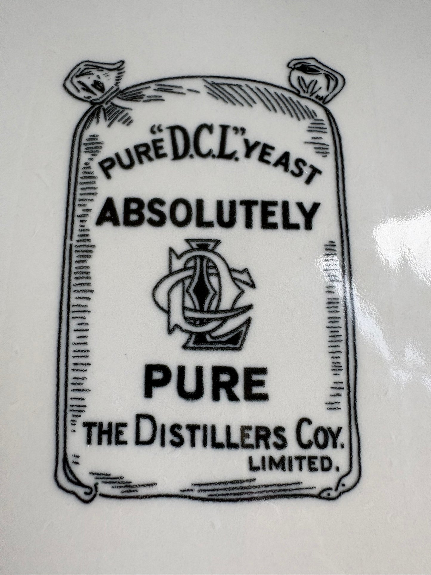 A close-up of a white surface printed with a vintage-style label design reading 'PURE D.C.L. YEAST