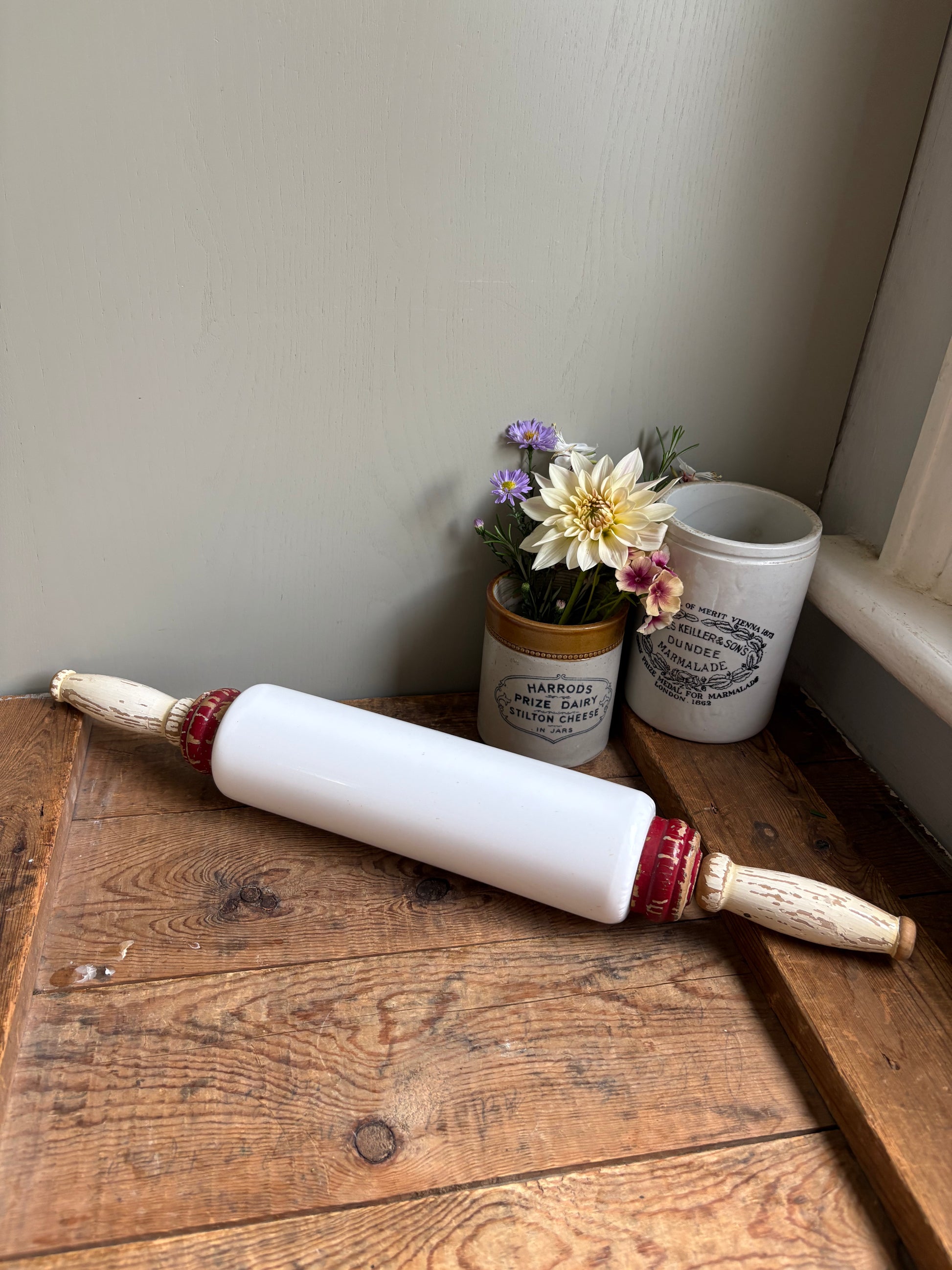 Antique 1920s milk glass rolling pin by Imperial Mfg Co with wooden handles, displayed on a farmhouse dresser.