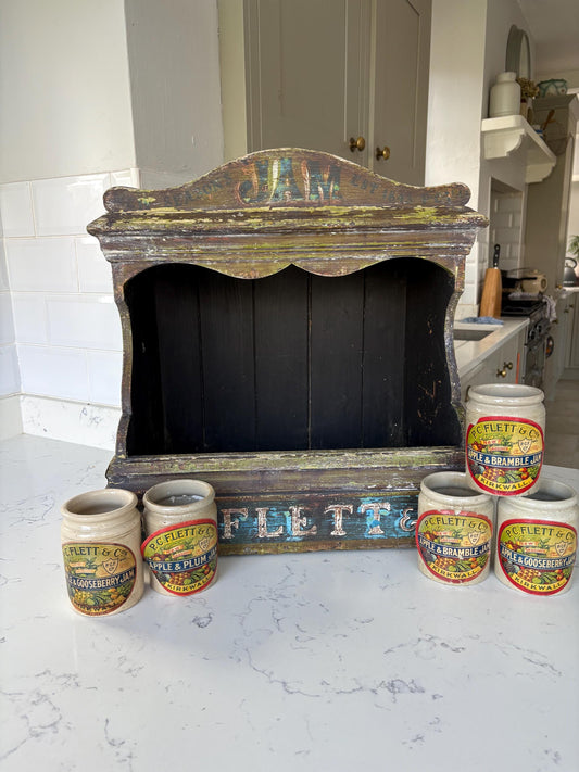 A vintage shop display for jam with five stone pots.
