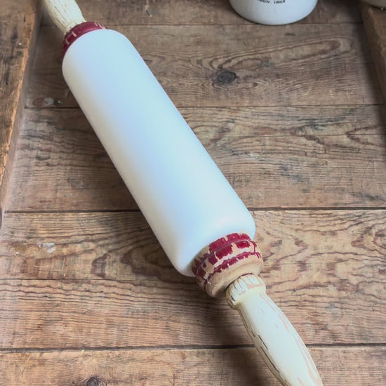 Antique 1920s milk glass rolling pin by Imperial Mfg Co with chippy wooden handles, displayed on a farmhouse dresser.