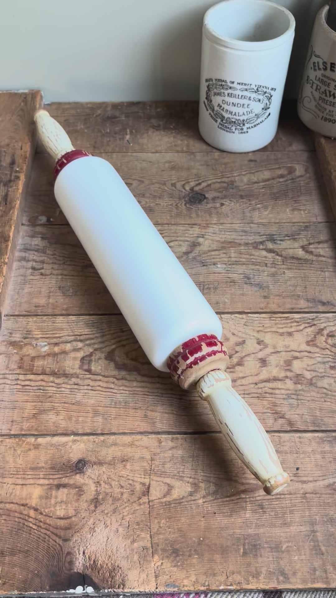 Antique 1920s milk glass rolling pin by Imperial Mfg Co with chippy wooden handles, displayed on a farmhouse dresser.
